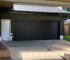 Black garage door with vertical panels and windows above